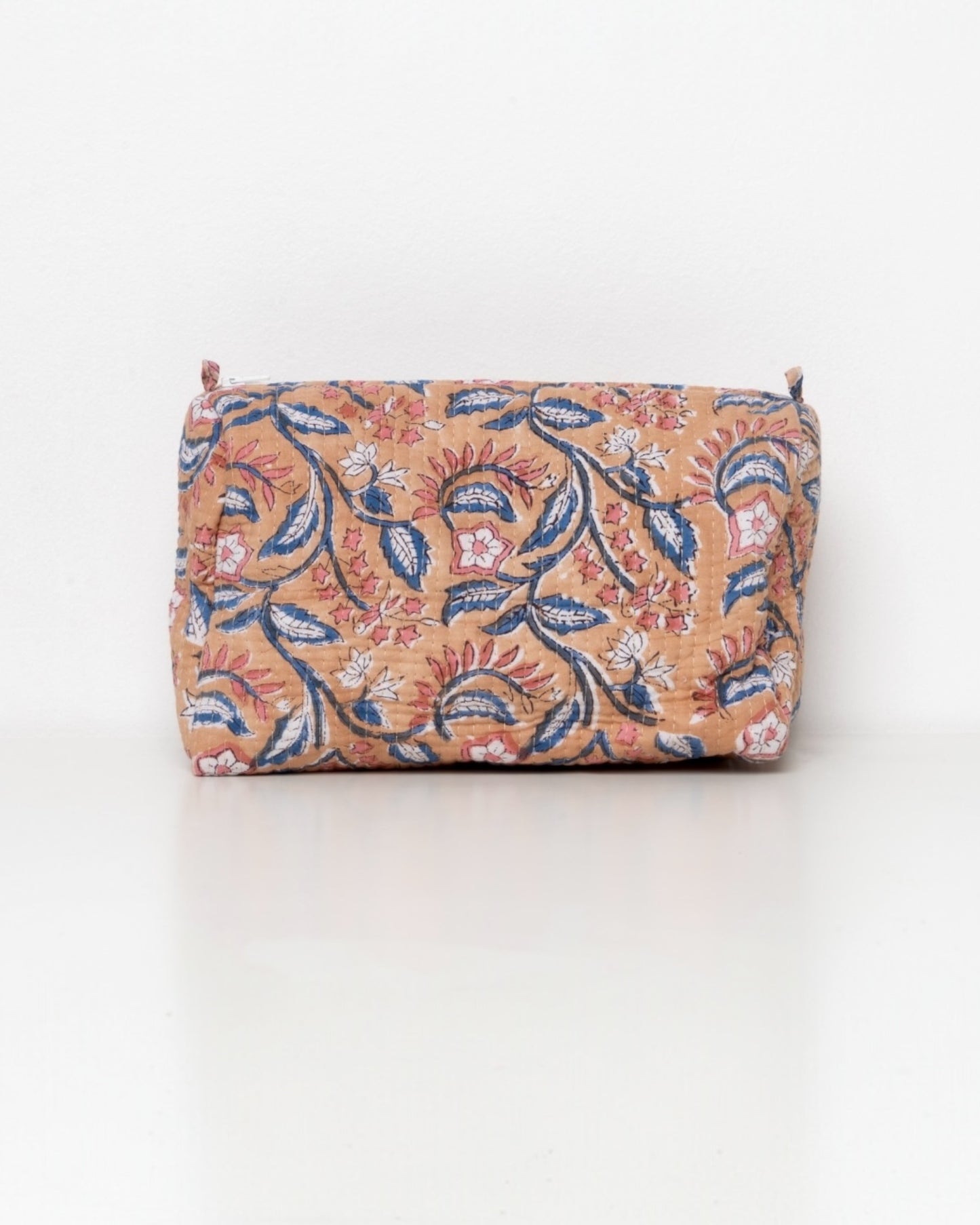 Trousse grande con fiori rosa e blu su fondo albicocca.