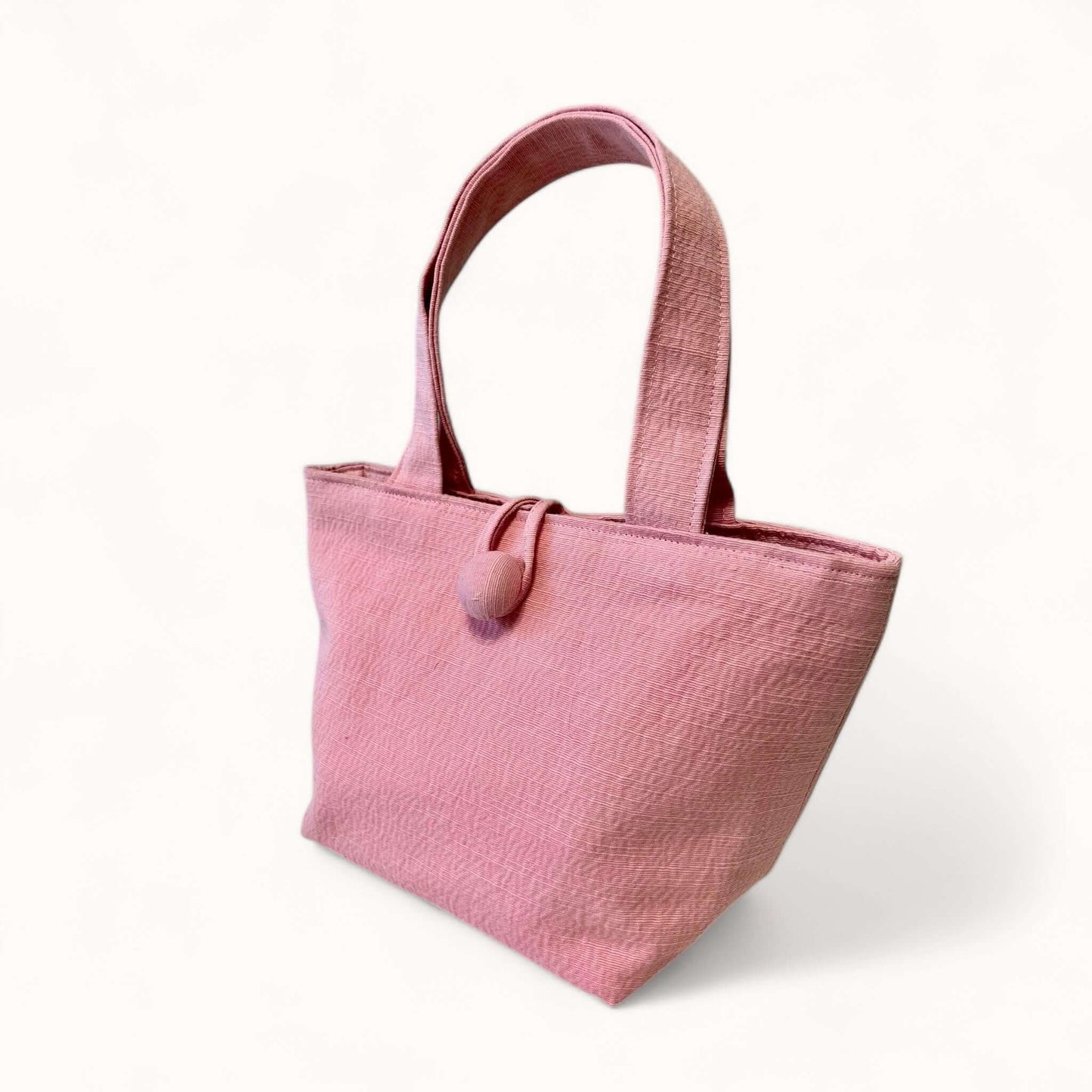 Piccola borsa a trapezio con tessuto morbido e superficie a coste, accessorio perfetto per completare un outfit da città con classe.