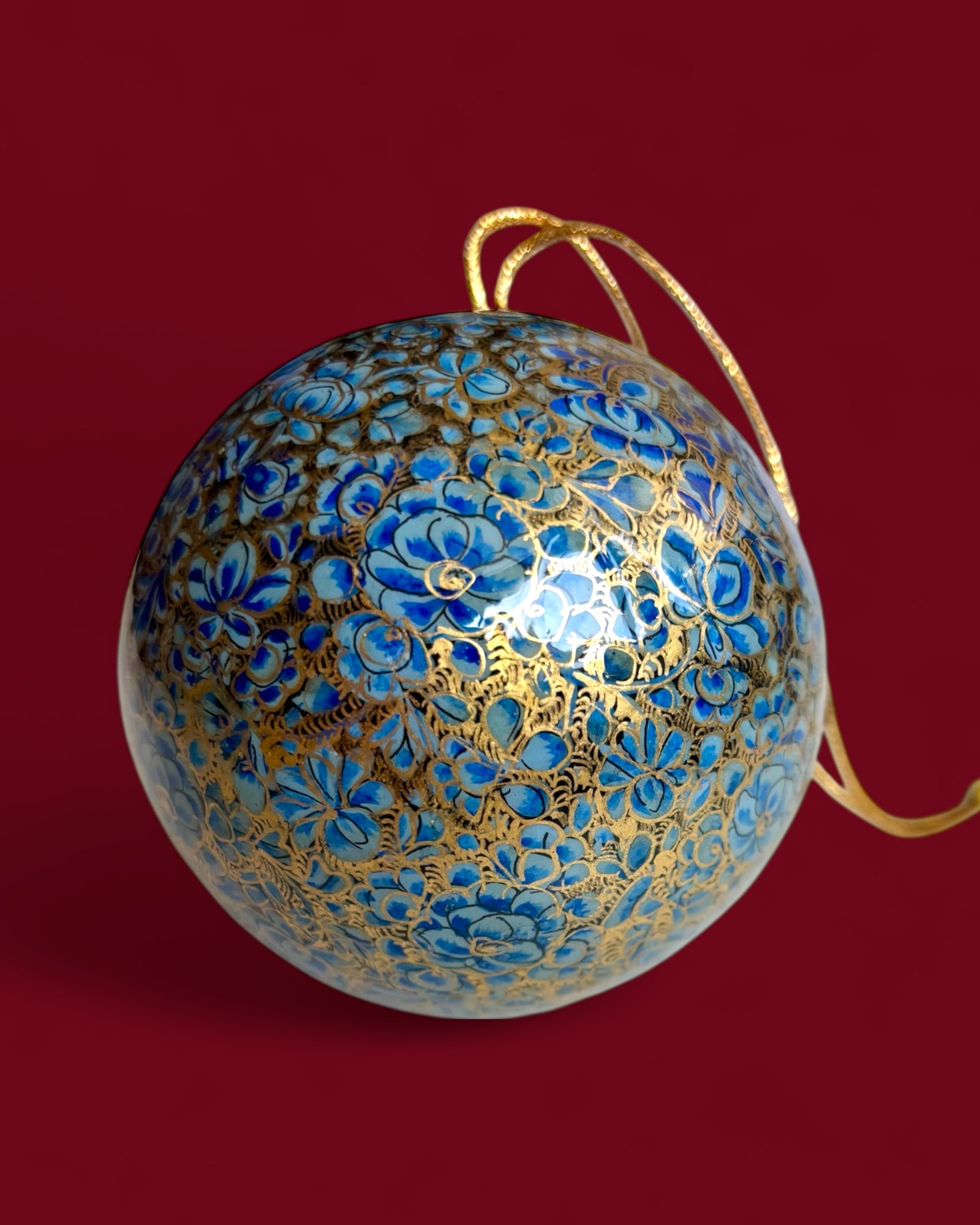 Pallina di Natale blu e oro con fiori dipinti a mano.