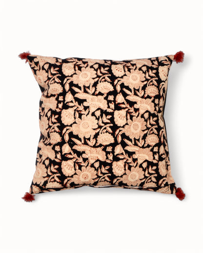 Handmade Indian cotton cushion cover with ochre, red, and black printed border and decorative red pom-poms.