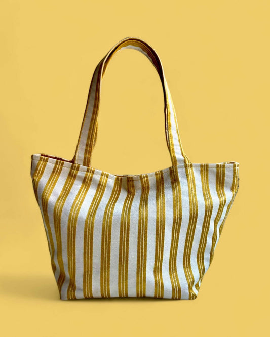 Borsa piccola e versatile con tessuto lucido e morbido, realizzata in raso di cotone panna con eleganti righe verticali giallo-oro.