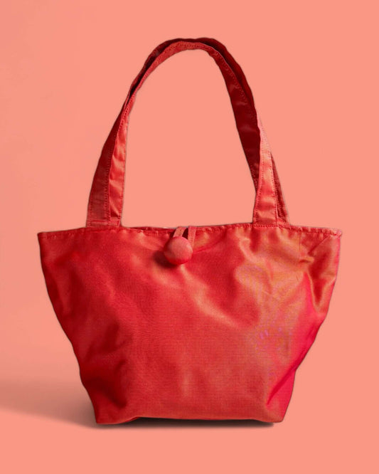 Minibag a mano in tessuto cangiante rosso-aranciato con effetto metallizzato, ideale per outfit serali eleganti.