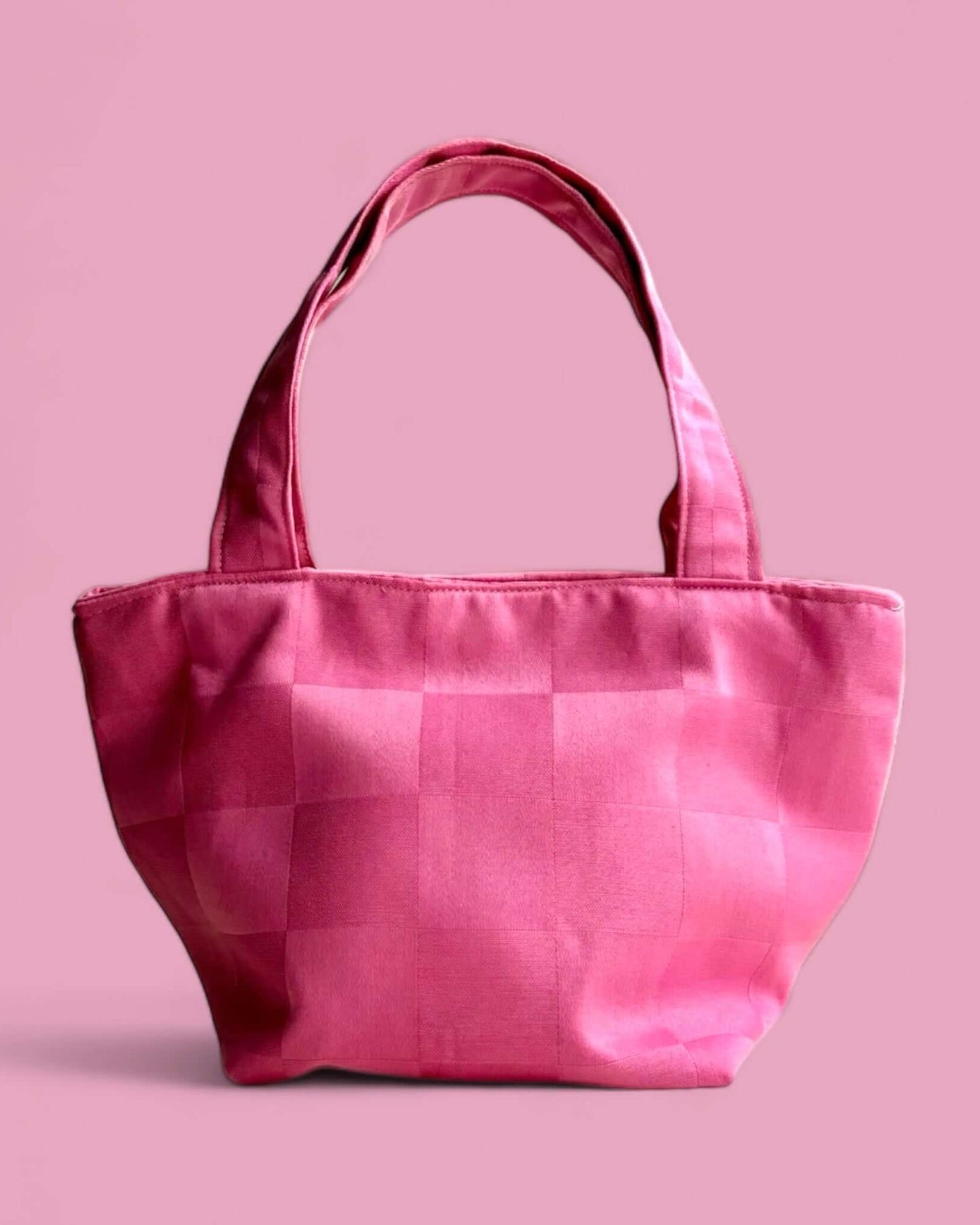 Borsa a mano rosa in cotone recuperato con fantasia a quadri, design compatto a trapezio rovesciato, ideale per occasioni eleganti e serate fuori.