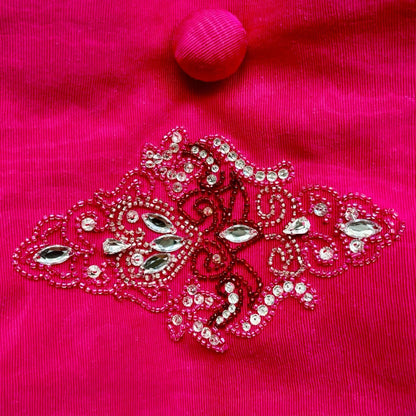 Ricamo a mano con pietre e strass su borsetta da sera fucsia.