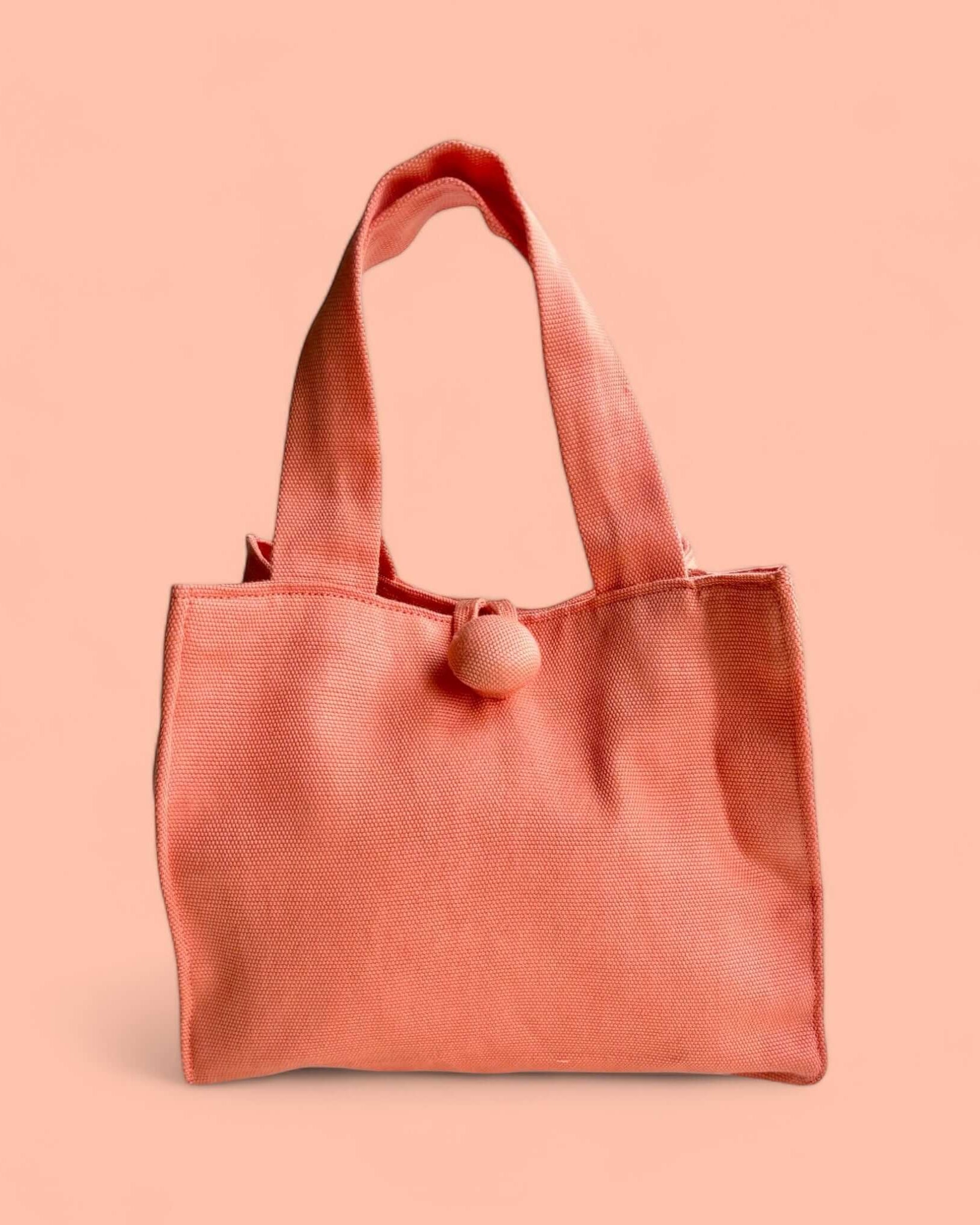 Borsa Leopolda in tessuto color pesca, con design quadrato e manici corti, ideale per un outfit chic e sofisticato.