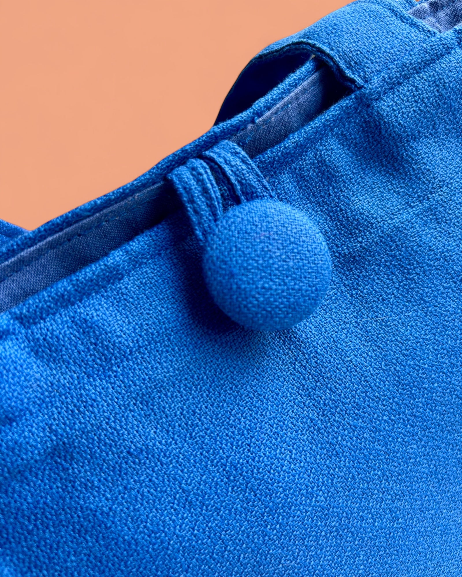Borsetta in cotone blu elettrico a forma di trapezio rovesciato, con bottone rivestito