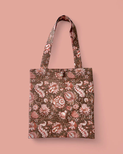 Borsa shopper in tessuto con motivo floreale bianco e pesca su fondo terracotta, realizzata con tecnica rajasthana del block printing.