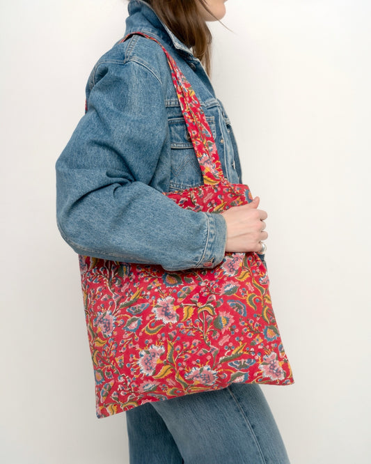 Borsa shopper in cotone stampato a mano, con fantasia floreale multicolor su fondo rosso.